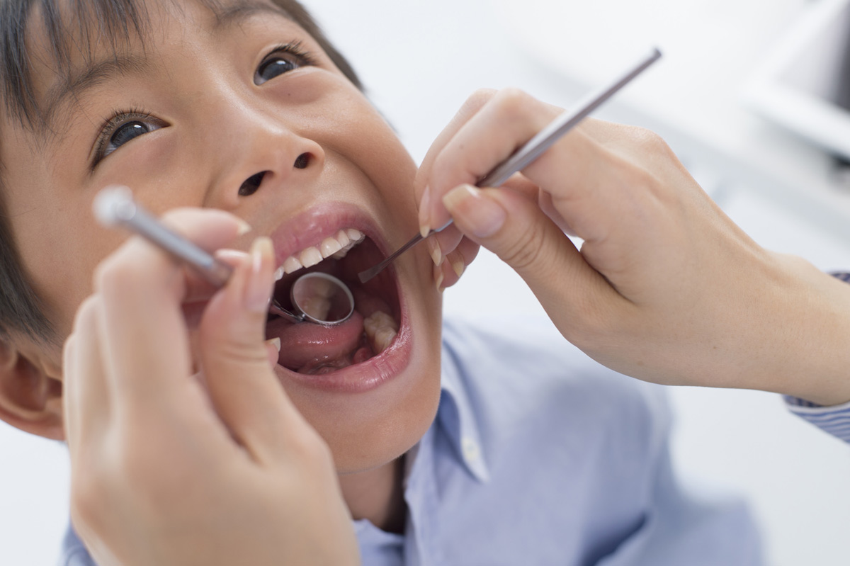 A young boy is examined for dental caries.