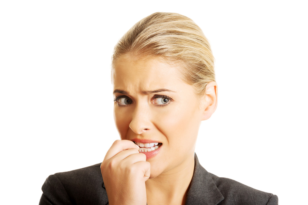 A young blond woman chews her nails out of stress, a habit our Placerville dentists discourage.